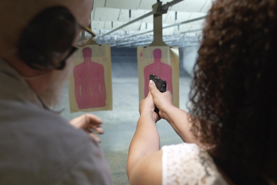 In this Aug. 21, 2021, image taken from video, Valerie Rupert is instructed on the proper way of using a fire arm at the Recoil Firearms store in Taylor, Mich. Rupert was among 1,000 or so mostly Black women taking part in free weekend gun safety and shooting lessons at two Detroit-area ranges. Black women like Rupert increasingly are considering gun ownership for personal protection, according to industry experts and gun rights advocates. (AP Photo/Carlos Osorio)