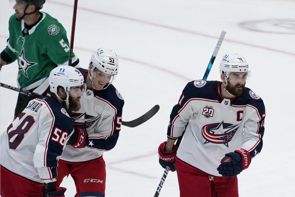 Columbus Blue Jackets defenseman David Savard (58), defenseman Gabriel Carlsson (53) and left wing Nick Foligno (71) celebrate a goal scored by Boone Jenner during the second period of the team's NHL hockey game against the Dallas Stars in Dallas, Thursday, March 4, 2021. Savard and Foligno were credited with the assists. Stars' Andrej Sekera skates to the bench after the play. (AP Photo/Tony Gutierrez)