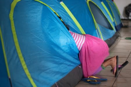 Flor, a 9-year old Guatemalan girl returned to Mexico to await her asylum hearing, dives into a tent in a migrant shelter in Tijuana