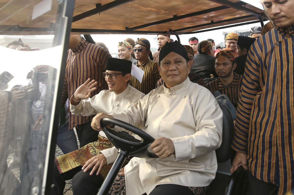 Indonesian presidential candidates Prabowo Subianto, center right, rides a golf cart and his running mate Sandiaga Uno during a ceremony marking the kick off of the campaign period for next year's election in Jakarta, Indonesia, Sunday, Sept. 23, 2018. Indonesia is set to hold its presidential and parliamentary election poll in April 2019.(AP Photo/Tatan Syuflana)