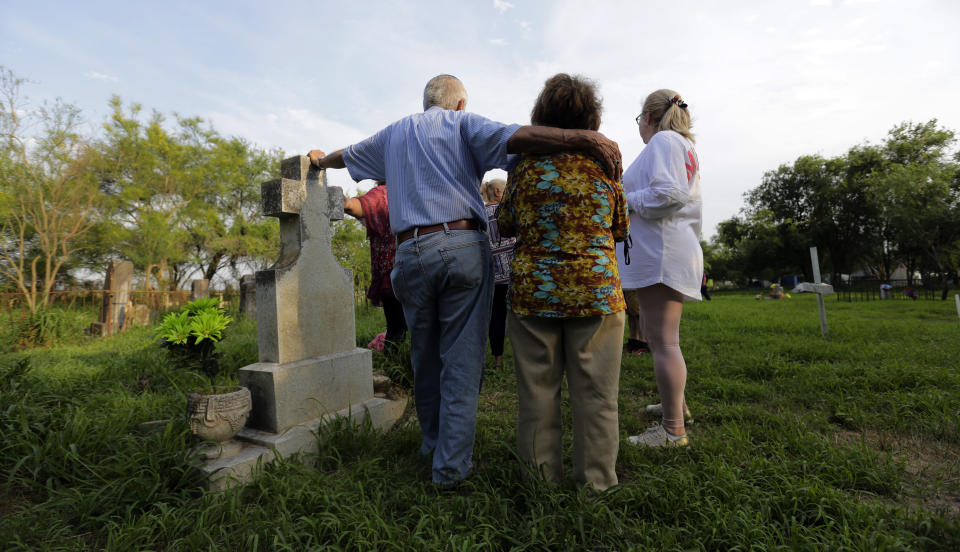 In this Wednesday, May 1, 2019, photo, Oliverio Yarrito, 80, left, stands with his wife, Odilia Yarrito, 79, as they visit family members among the gravestones at the Eli Jackson Cemetery in San Juan, Texas. (AP Photo/Eric Gay)