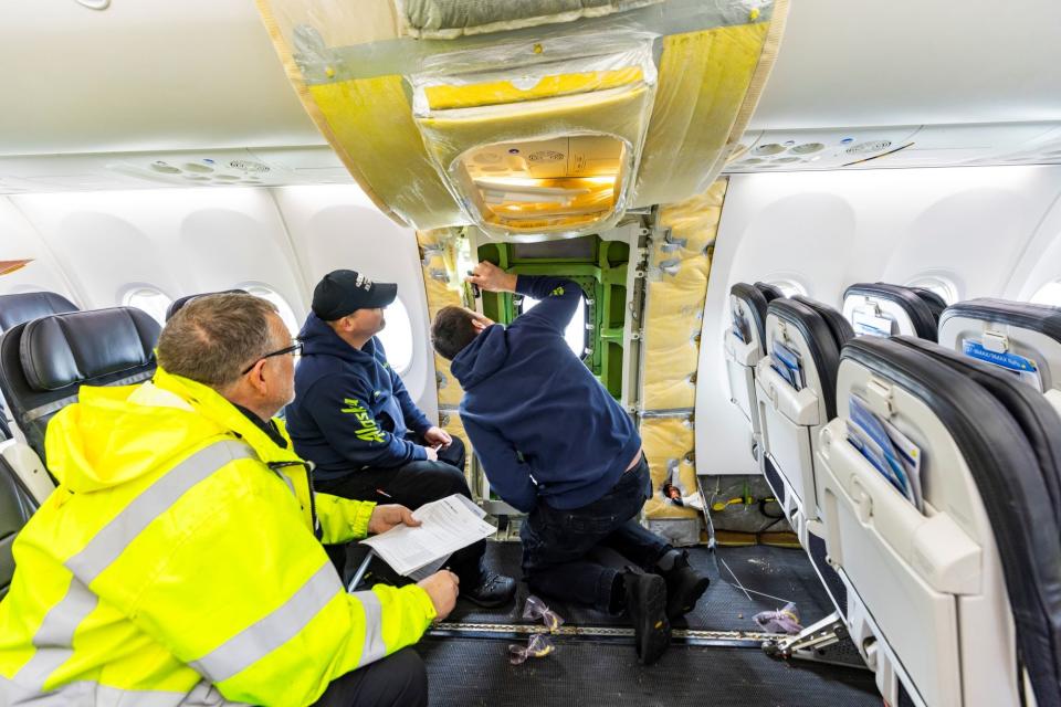 Alaska Airlines mechanics inspect the door plug on a 737 Max.