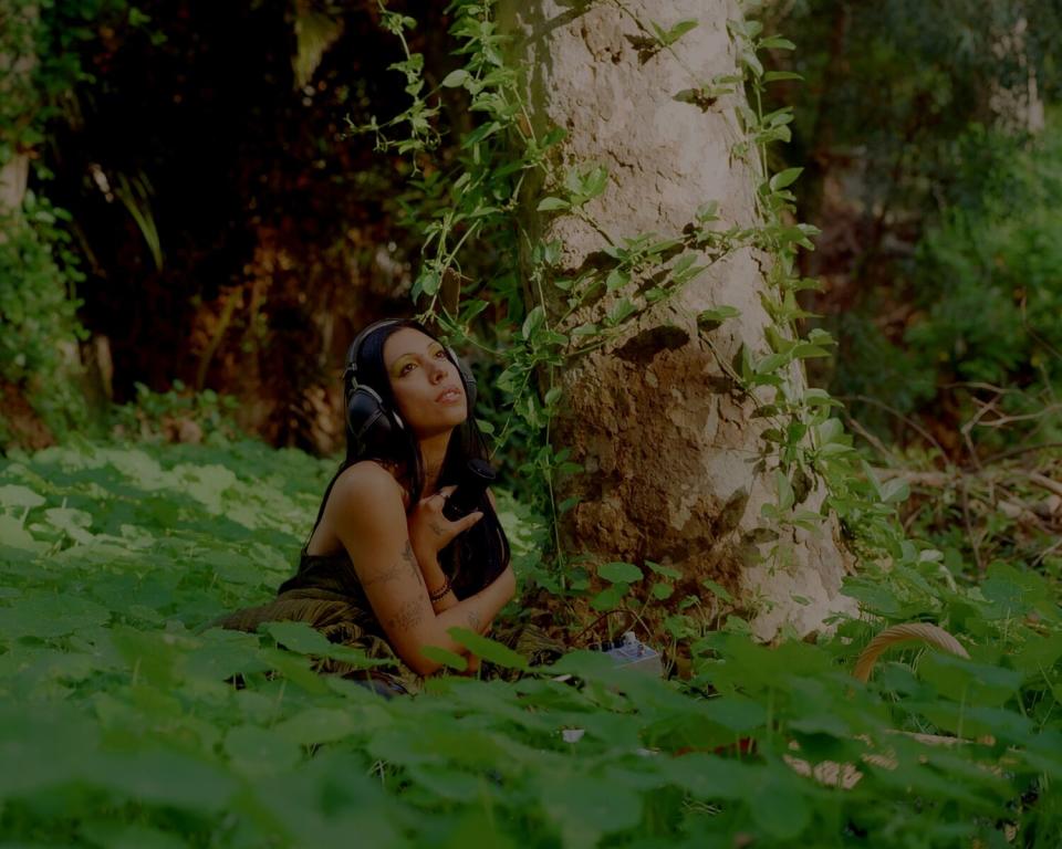 Mia Carucci sits on the forest floor.