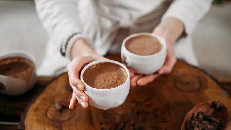 holding mugs of hot chocolate