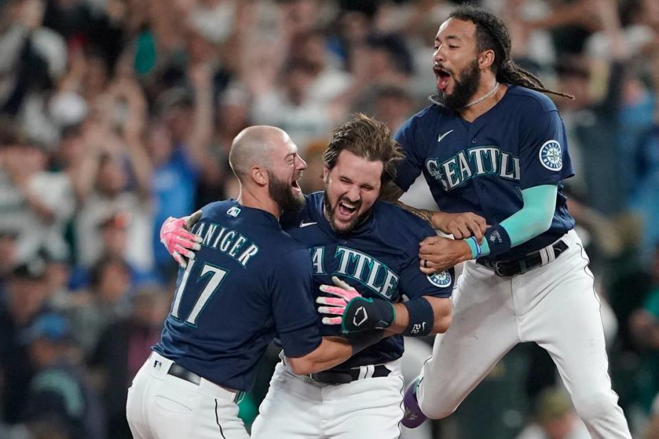 Seattle Mariners’ Luis Torrens, center, is greeted by teammates Mitch Haniger, left, and J.P. Crawford, right, after Torrens hit a walk-off RBI single to give the Mariners a 1-0 win over the New York Yankees in a 13-inning baseball game, Tuesday, Aug. 9, 2022, in Seattle. (AP Photo/Ted S. Warren)