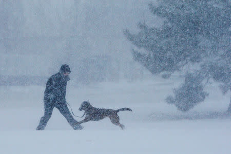 A man and his dog play in the snow during a winter snowstorm in the Boston suburb of Revere, Massachusetts. REUTERS/Brian Snyder