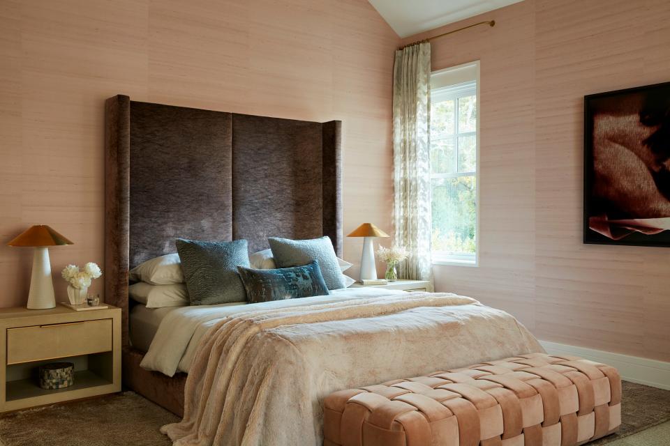 “I love the fur and the pink and the swinging sofa,” says Lau about her beloved primary bedroom, which is covered in Phillip Jeffries Sunset Silk Shale Pink wallpaper. “I already have wonderful memories of me and my kid jumping on the bed here—I love it so much.” The RH bedside tables and Kelly Wearstler Miramar table lamps surround the towering, textural custom headboard upholstered in Myung Jin Mirage taupe velvet fabric. The plush pink Eric Kuster Conran pouffe adds another moment of fun. The artwork on the wall is Louise, version 2 by Matt Saunders.