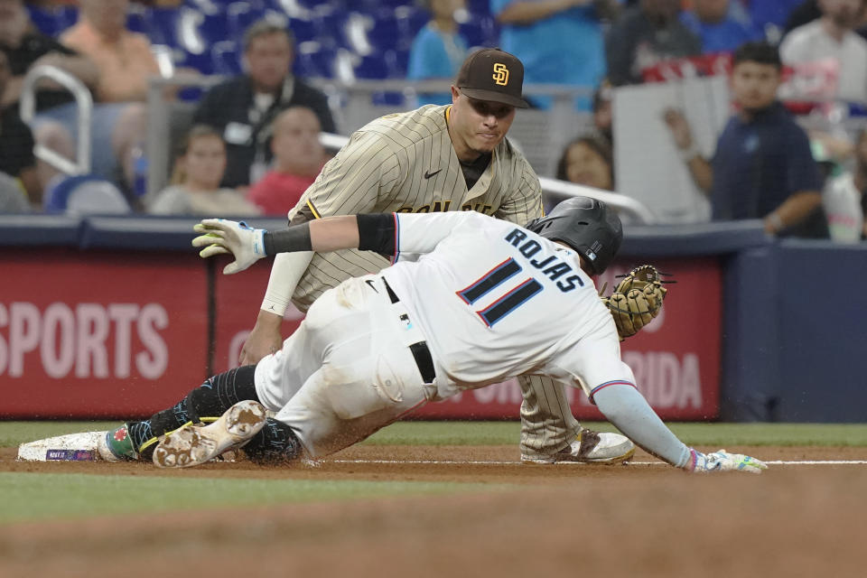 Miami Marlins' Miguel Rojas (11) slides safely into third base on a triple as San Diego Padres third baseman Manny Machado (13) is late with the tag in the sixth inning of a baseball game, Monday, Aug. 15, 2022, in Miami. (AP Photo/Marta Lavandier)