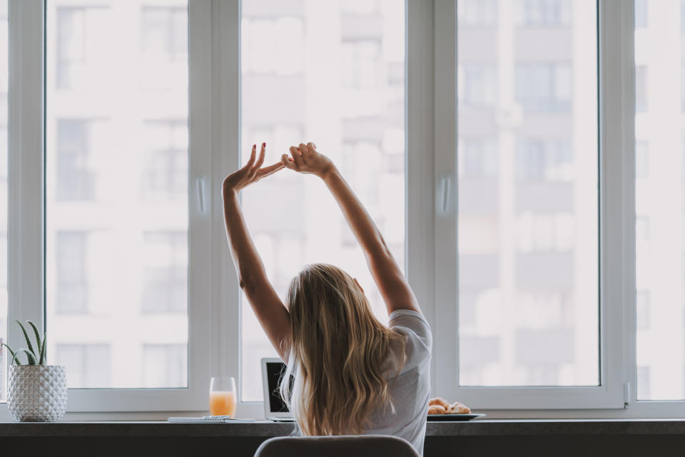 Frau vor Fenster macht Stretching