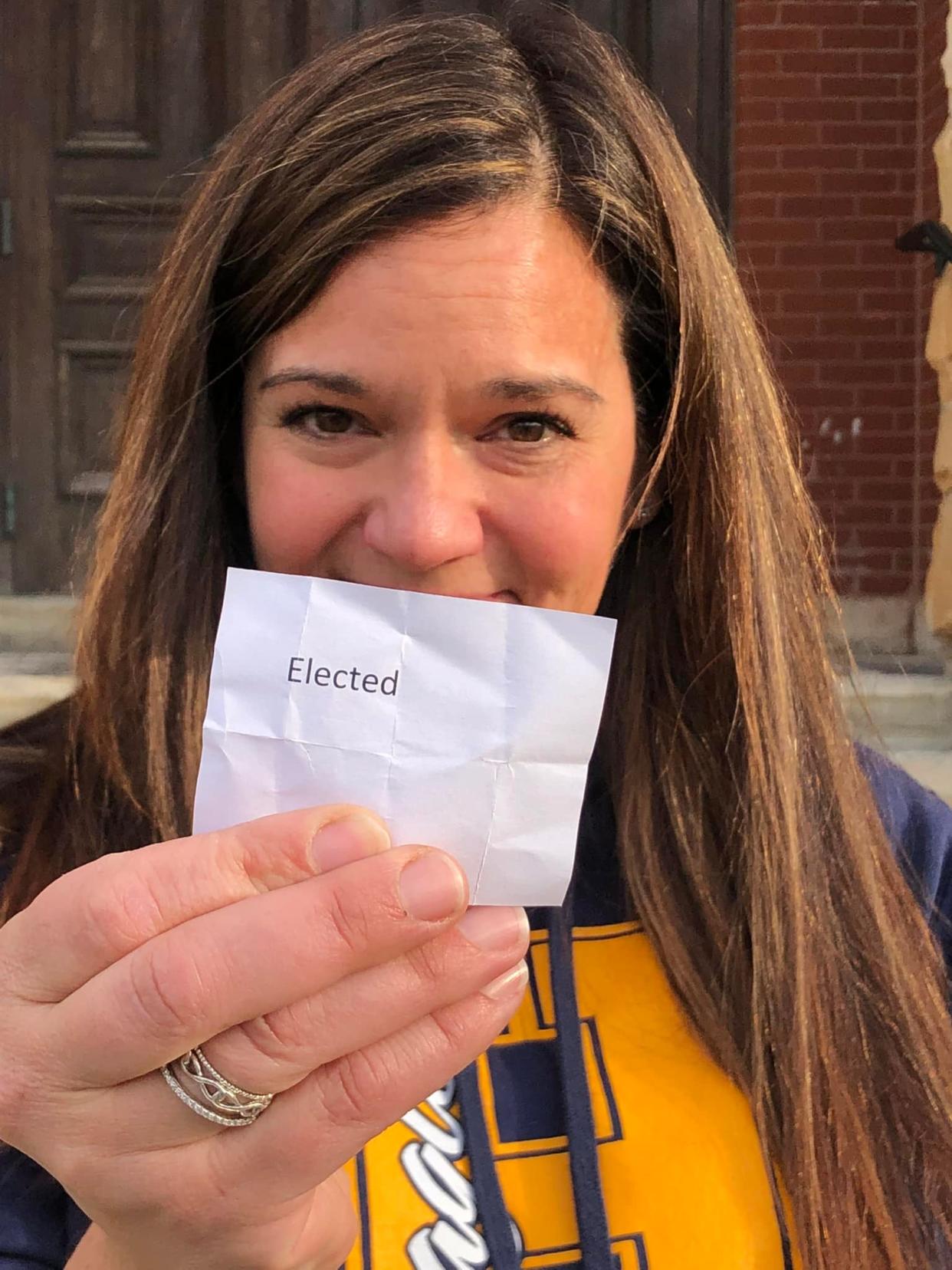 Hartland Consolidated School Board Trustee Michelle Hemeyer holds a piece of paper indicating she is elected after a tie with candidate Greg Keller outside the historic Livingston County courthouse in Howell on Friday, Nov. 11, 2022.