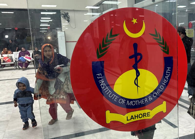 A woman with a child enters the mother and child unit of a teaching hospital in Lahore