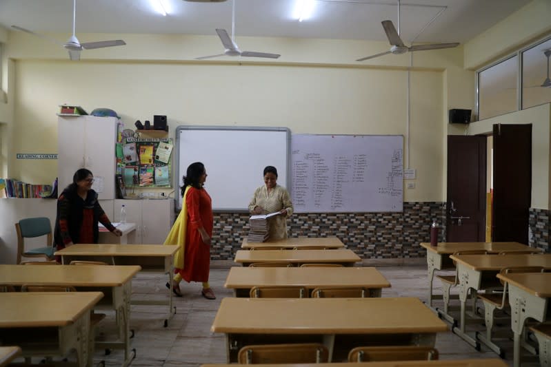 Teachers talk to each other in an empty classroom of a school after it remained closed on account of smog in New Delhi