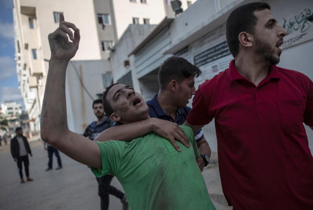 A Palestinian man reacts to the death of his father who was killed by an Israeli airstrike that destroyed the upper floors of a commercial building and caused damage to the nearby Health Ministry and prime health care clinic in Gaza City on Monday, May 17, 2021.