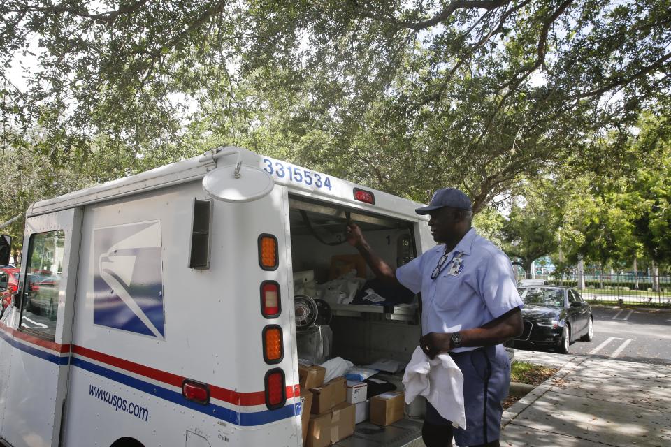 FILE - In this June 14, 2018, file photo, Elston Bradshaw, a mail carrier for the United States Postal Service closes a mail truck door after delivering mail to an apartment complex in Aventura, Fla. People tend to spend a lot of time planning their holiday travel but not a lot preparing for their return home. Have your mail and subscriptions placed on hold so things don't accumulate at your front door, tipping off potential thieves that you're away.(AP Photo/Brynn Anderson, File)