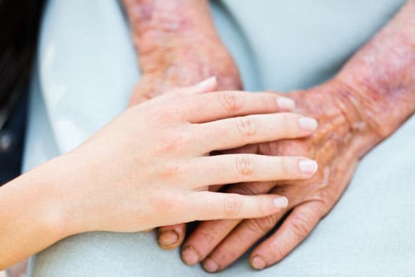 Caring woman hands over elderly hands