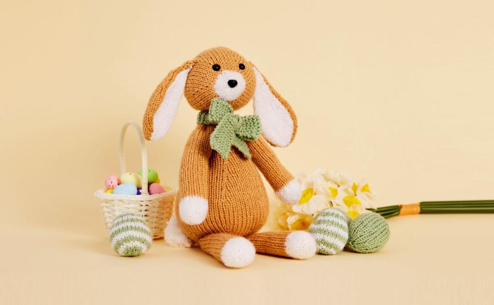 knitted easter bunny and easter eggs on yellow background
