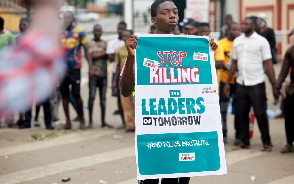 A boy holds a banner during a protest against the Nigeria rogue police - AKINTUNDE AKINLEYE/EPA-EFE/Shutterstock