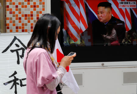 A woman walks past a sign printed with the characters of the name of the new Japanese imperial era Reiwa next to a television screen showing North Korea's leader Kim Jong Un during a news report on North Korea firing several short-range projectiles from its east coast, in Tokyo, Japan May 4, 2019. REUTERS/Kim Kyung-Hoon