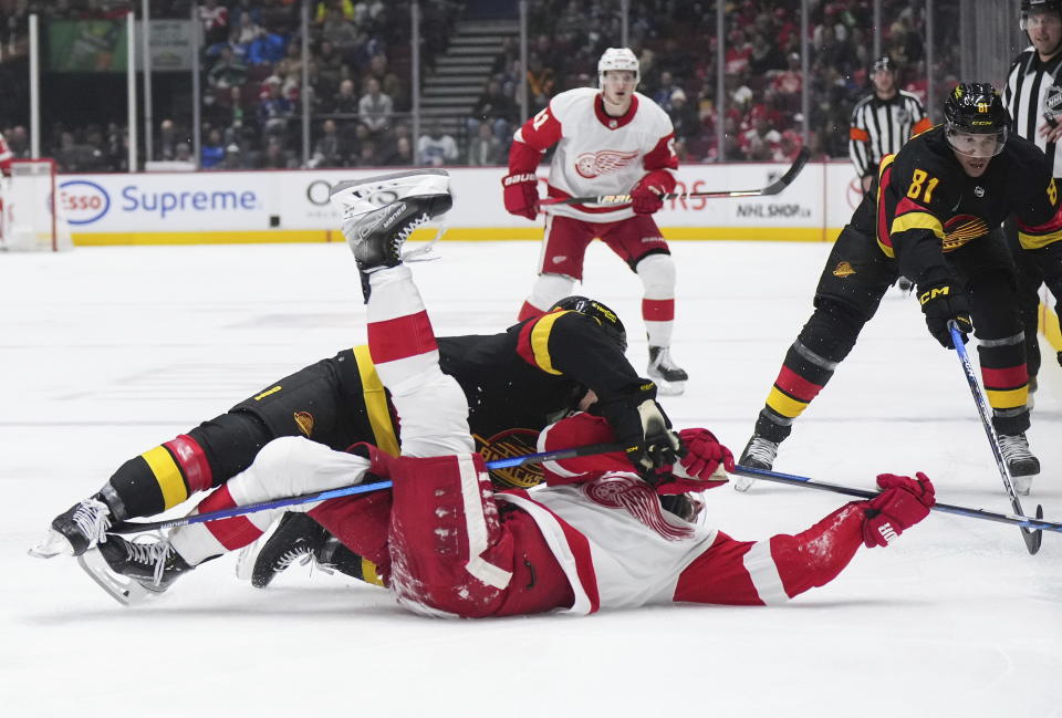 Vancouver Canucks' Sheldon Dries, front top left, checks Detroit Red Wings' Dylan Larkin, front bottom left during the second period of an NHL hockey game in Vancouver, British Columbia, Monday, Feb. 13, 2023. (Darryl Dyck/The Canadian Press via AP)