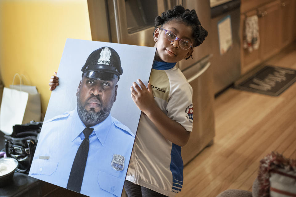 Amethyst, Erin "Toke" Tokley's five year old daughter, holds a photo of her father, on Aug. 29, 2021, in Secane, Pa. Tokley — “Toke” to his friends and family — died on March 3, becoming the Philadelphia Police Department's sixth confirmed COVID-19 death. (AP Photo/Laurence Kesterson)