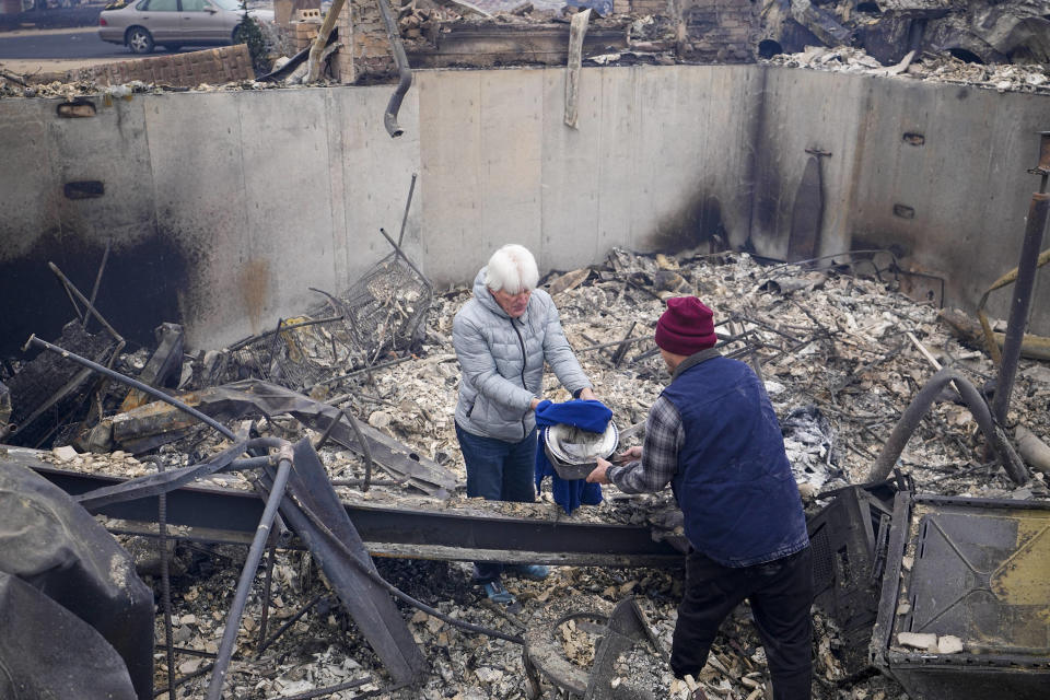 John Peer finds a couple of plates as he looks through the rubble of his fire-damaged home after the Marshall Wildfire in Louisville, Colo., Friday, Dec. 31, 2021. (AP Photo/Jack Dempsey)