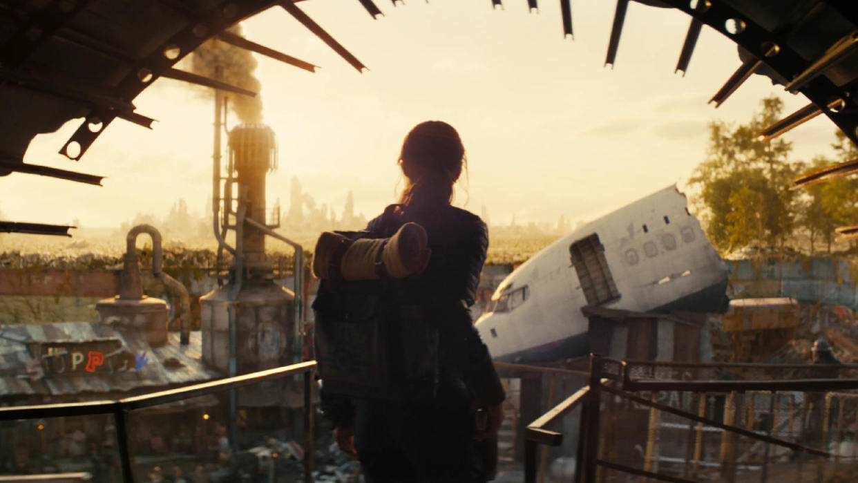  Silhouette of a person looking out onto a ruined landscape. 