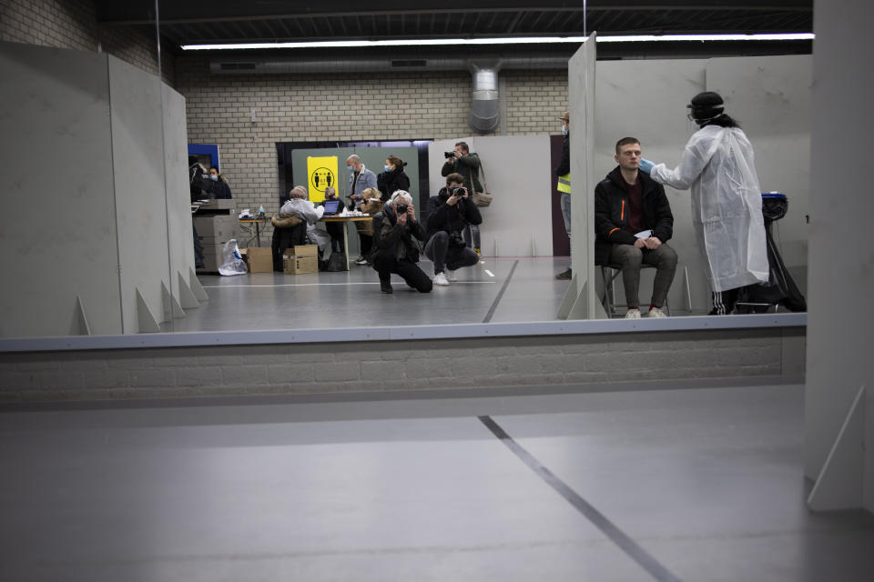 Photjournalists take pictures as a man gets a nose and throat swab as residents of Bergschenhoek, Netherlands, take part in a mass test of all of the municipality's 62,000 inhabitants starting Wednesday, Jan. 13, 2021, following a cluster of COVID-19 cases at an elementary school, including about 30 cases of the British coronavirus variant. (AP Photo/Peter Dejong)