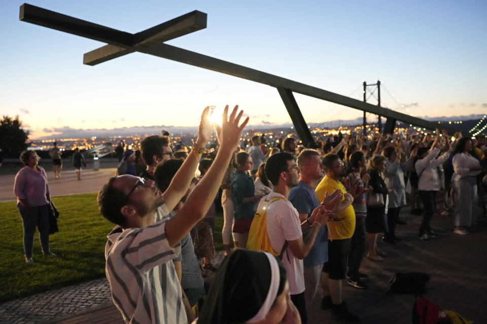 FILE - Faithful sing Christian songs before a vigil attended by people arriving early for the World Youth Day at a viewpoint overlooking Lisbon from across the Tagus River, in Almada, Portugal, as night falls, Friday, July 28, 2023. When Pope Francis made the first foreign trip of his papacy, to Rio de Janeiro for World Youth Day in 2013, he urged young people to make a "mess" in their local churches, to shake things up even if it ruffled the feathers of their bishops. (AP Photo/Armando Franca, File)