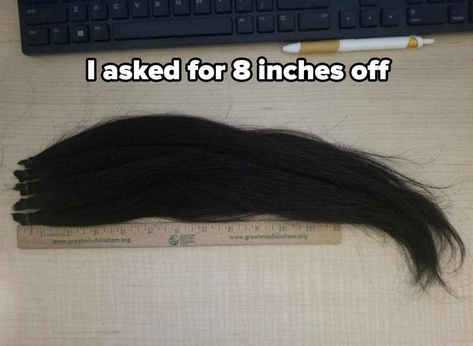 Hair extensions laid on a desk next to a ruler and pen, showcasing their length