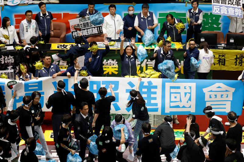 Lawmakers from the the largest opposition party Kuomintang (KMT) try to block plastic bags, some with a text reading “trash”, that were thrown by lawmakers from the Democratic Progressive Party (DPP), during a session at the Parliament in Taipei