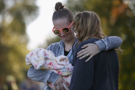 Ashley Katter, 30, (L) hugs Umpqua Community College student Haley Lamphere, 23, during a candlelight vigil for victims of the Umpqua Community College shooting, in Winston, Oregon, United States, October 3, 2015. REUTERS/Lucy Nicholson