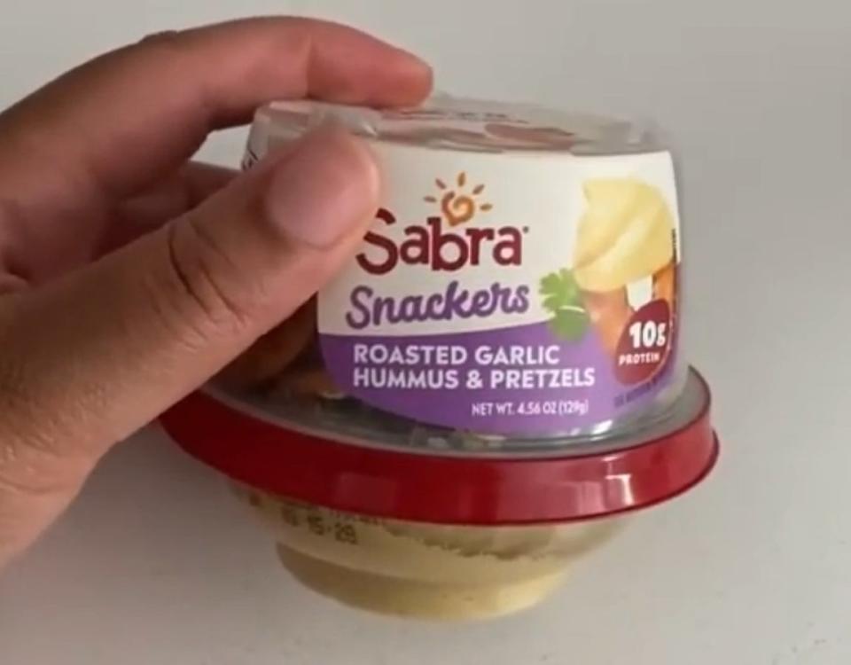 Woman holding travel hummus