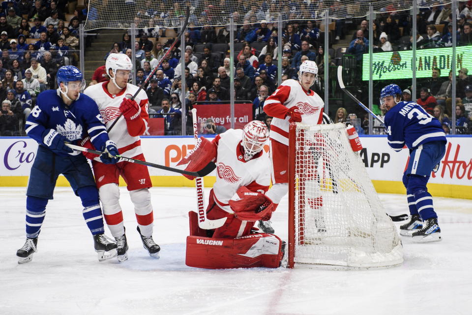 Detroit Red Wings goaltender Alex Nedeljkovic (39) makes a save on Toronto Maple Leafs left wing Michael Bunting (58) as Red Wings' Ben Chiarot (8) defends during the second period of an NHL hockey game in Toronto on Sunday, April 2, 2023. (Christopher Katsarov/The Canadian Press via AP)