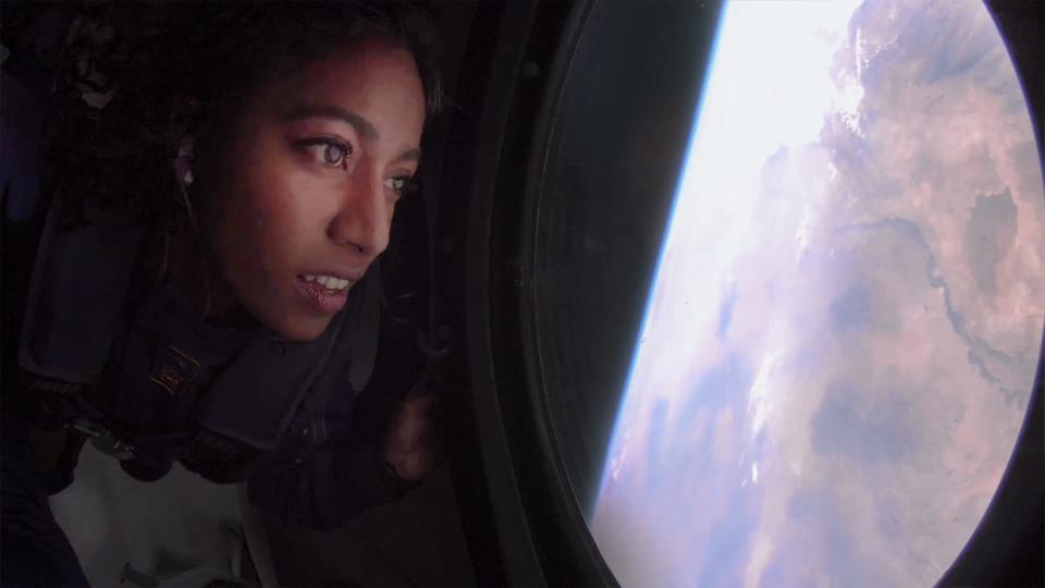 A Virgin Galactic astronaut looks out the window toward earth