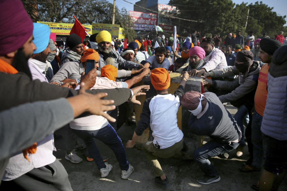 FILE - In this Friday, Nov. 27, 2020, file photo, protesting farmers remove a concrete barricade set up by policemen as they attempt to move towards Delhi, at the border between Delhi and Haryana state. They are demanding the repeal of laws passed by Parliament in September that they say will favor large corporate farms, devastate the earnings of many farmers and leave those who hold small plots behind as big corporations win out. (AP Photo/Altaf Qadri, File)