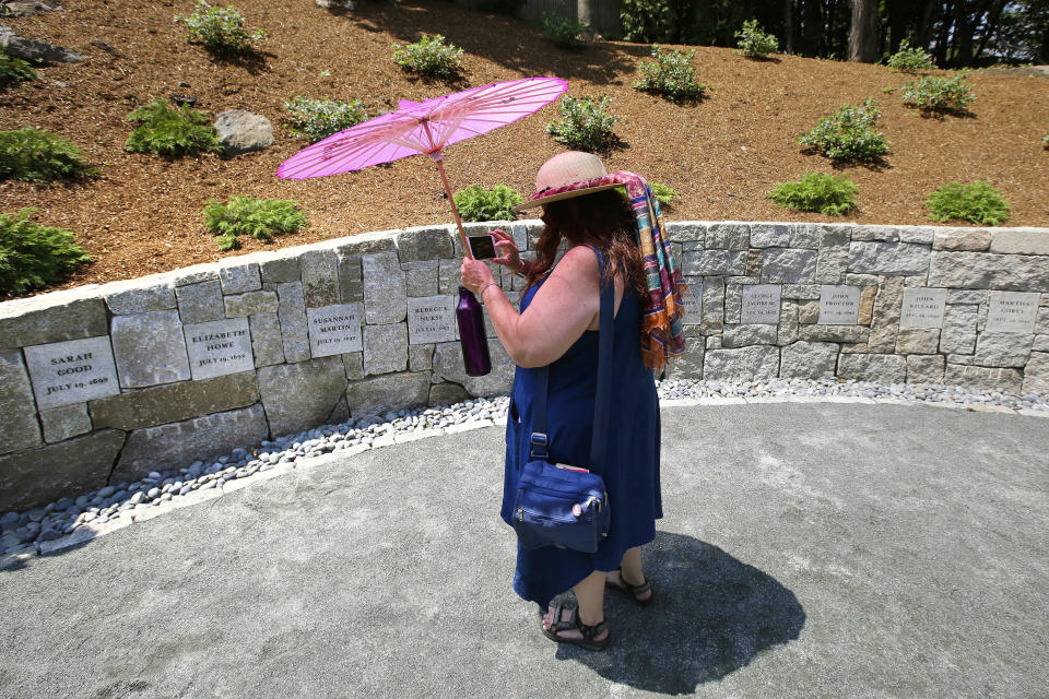 FILE - In this July 19, 2017, file photograph, Karla Hailer, a fifth-grade teacher from Scituate, Mass., shoots a video where a memorial stands at the site in Salem, Mass., where five women, including Elizabeth Johnson Jr., were hanged as witches more than 325 years earlier. In 2021, Massachusetts lawmakers formally exonerated Elizabeth Johnson Jr. 329 years after she was convicted of witchcraft in 1693 and sentenced to death at the height of the Salem Witch Trials. Johnson is believed to be the last accused Salem witch to have her conviction set aside by legislators. (AP Photo/Stephan Savoia, File)
