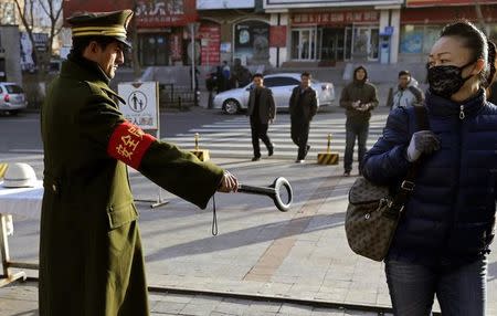 A pedestrian reacts as a security officer holds out a detector on a street in Urumqi, Xinjiang Uighur autonomous region, November 17, 2013. REUTERS/Rooney Chen