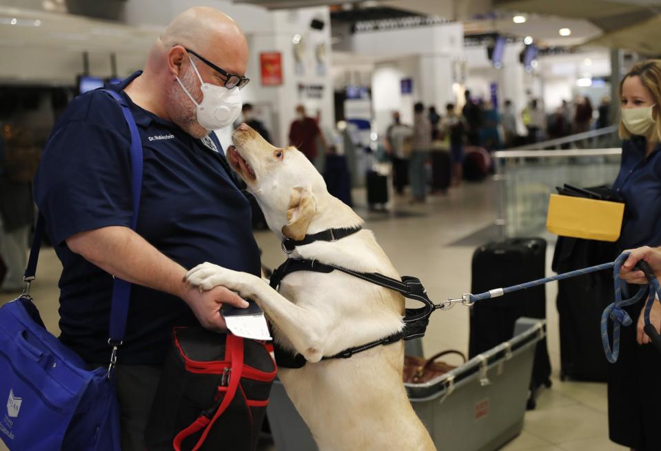 Dr. Rubinstein gets a greeting from a fellow American passenger's dog, named Dumas, as people prepare to board a flight to Miami, Fla., from the Silvio Pettirossi airport in Luque, on the outskirts of Asuncion, Paraguay, April 23, 2020. (AP Photo/Jorge Saenz)