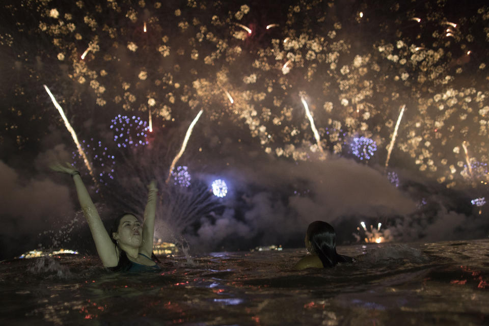 A woman watches the fireworks exploding over Copacabana Beach during the New Year's celebrations in Rio de Janeiro, Brazil, Tuesday, Jan. 1, 2019. (AP Photo/Leo Correa)