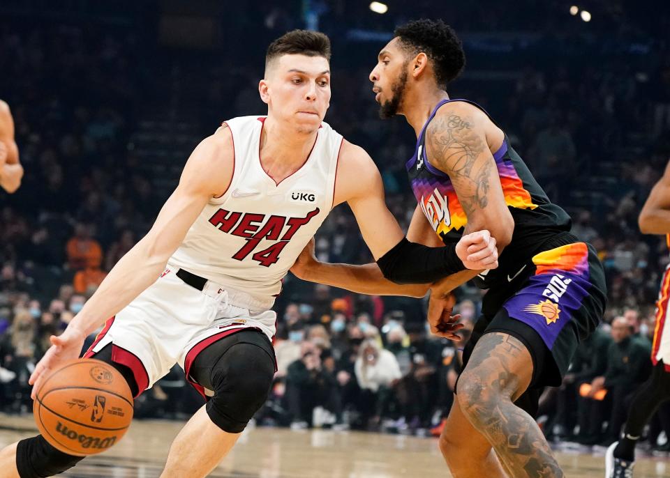 Miami Heat's Tyler Herro (14) drives around Phoenix Suns' Cameron Payne during the first half of an NBA basketball game Saturday, Jan. 8, 2022, in Phoenix. (AP Photo/Darryl Webb)