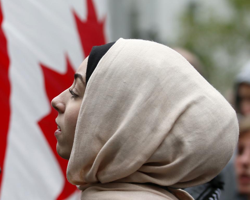 A demonstrator is framed by a Canadian flag as she protests against Quebec's proposed Charter of Values in Montreal, September 14, 2013. Thousands took to the streets to denounce the province's proposed bill to ban the wearing of any overt religious garb by government paid employees. REUTERS/ Christinne Muschi(CANADA - Tags: POLITICS CIVIL UNREST RELIGION)