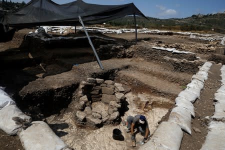 A man works next to a burial place at an excavation site where a huge prehistoric settlement was discovered by Israeli archaeologists in the town of Motza near Jerusalem