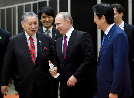 Russian President Vladimir Putin (C) holds a figure of Jigoro Kano, the founder of judo, presented from former Japanese Prime Minister Yoshiro Mori (L) beside Japanese Prime Minister Shinzo Abe (R) when he visits the Kodokan Judo Institute, the headquarters of the worldwide judo community, in Tokyo on December 16, 2016. REUTERS/Toru Yamanaka/Pool