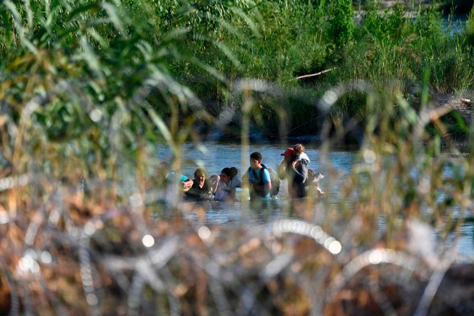 A migrant family from Venezuela is seen beyond concertina wire as they illegally cross the Rio Grande River in Eagle Pass, Texas, at the border with Mexico.