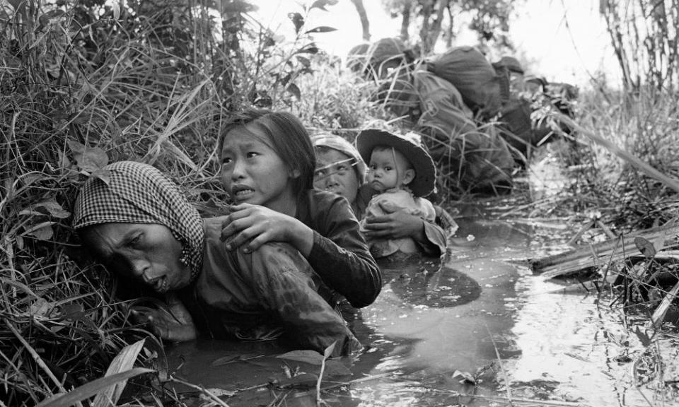 Women and children crouch in a muddy canal as they take cover from intense Viet Cong fire at Bao Trai, about 20 miles west of Saigon, Vietnam.