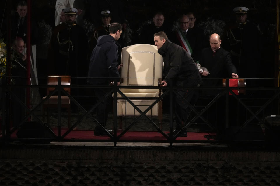 Vatican ushers carry away the Pope Francis' chair prior to the start of the Via Crucis (Way of the Cross) at the Colosseum on Good Friday, in Rome, Friday, March 29, 2024. (AP Photo/Gregorio Borgia)
