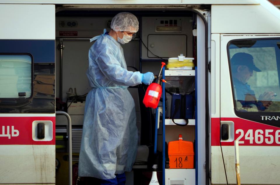 A medical worker wearing protective equipment sprays disinfectant at his ambulance after delivering a patient suspected of being infected with the coronavirus to the Pokrovskaya hospital in St.Petersburg, Russia, Monday, May 4, 2020. (AP Photo/Dmitri Lovetsky)