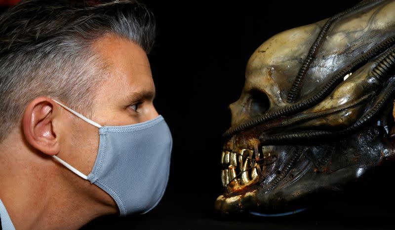 Stephen Lane, CEO of Prop Store, poses for a photograph with a special effects mechanical head from the film Alien at a preview of a movie and TV memorabilia auction in Rickmansworth