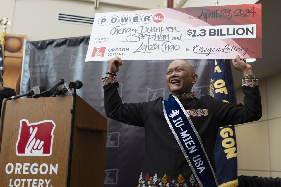 Cheng "Charlie" Saephan holds display check above his head after speaking during a news conference where it was revealed that he was one of the winners of the $1.3 billion Powerball jackpot at the Oregon Lottery headquarters on Monday, April 29, 2024, in Salem, Ore. (AP Photo/Jenny Kane)