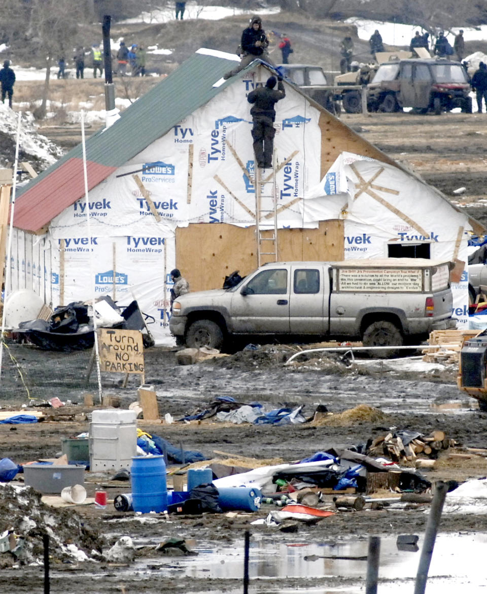 A law enforcement officer climbs a ladder to speak to one of the final holdouts of the Dakota Access Pipeline protest camp sitting atop a wood structure built at the Oceti Sakowin camp in Morton County Thursday, Feb. 23, 2017, near Cannon Ball, N.D. After a couple of hours the protester came down on his own and was arrested. (Mike McCleary/The Bismarck Tribune via AP, Pool)